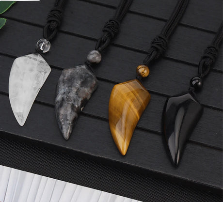 Four stone pendants on black cords with a brand logo in the corner.