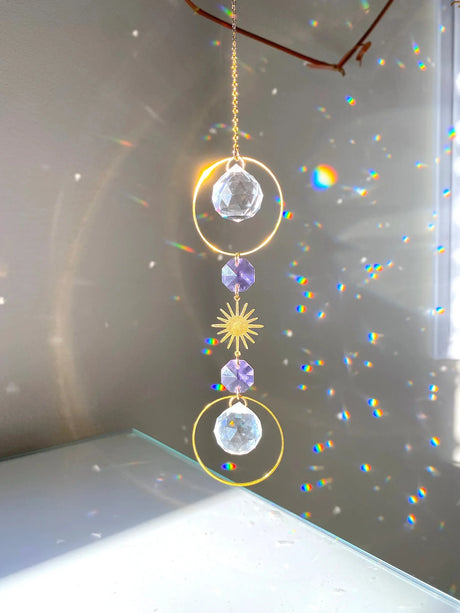 Decorative hanging crystal with rainbow effects on a reflective surface