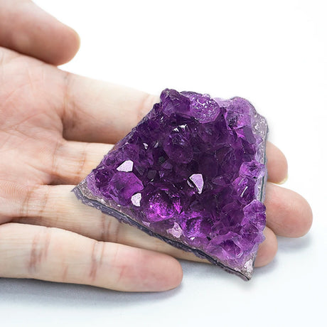 Hand holding a purple crystal rock on a white background