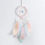 Pastel-colored dreamcatcher with feathers on a light gray background