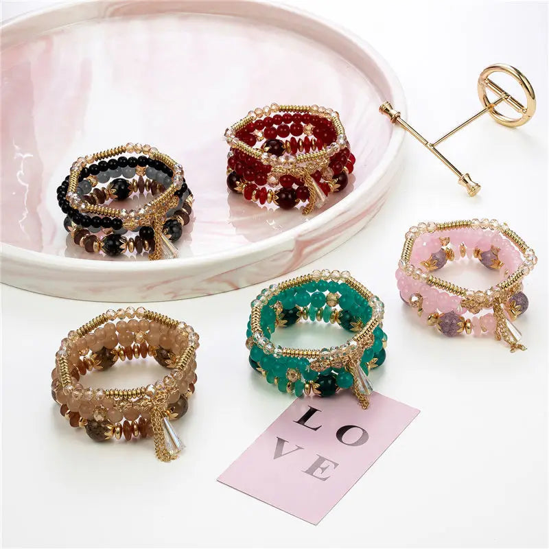 Colorful beaded bracelets on a white surface with a 'LOVE' card.