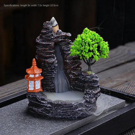 Decorative miniature landscape with a waterfall, trees, and a pagoda on a dark surface.