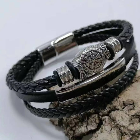 Black braided leather bracelet with silver metal accents on a light gray background