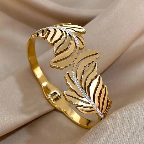Gold leaf-shaped bracelet on a beige fabric background