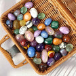 Assorted colorful gemstones in a wicker basket on a light background
