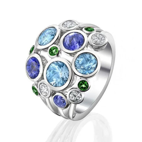 Silver ring with blue, green and clear gemstones on a white background