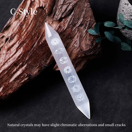 Crystal tool with engraved designs on a dark surface with a wooden log and green leaves.