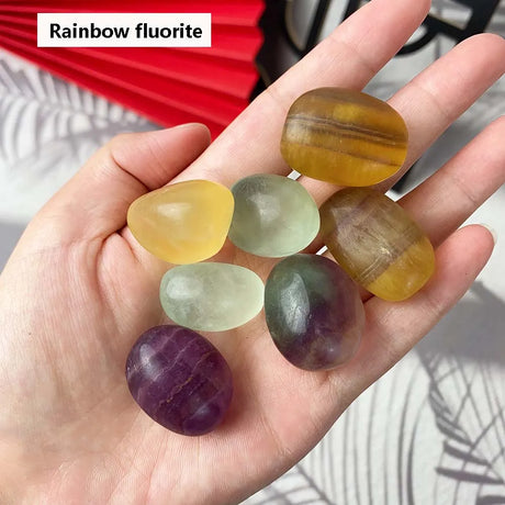 Hand holding rainbow fluorite stones with a blurred background