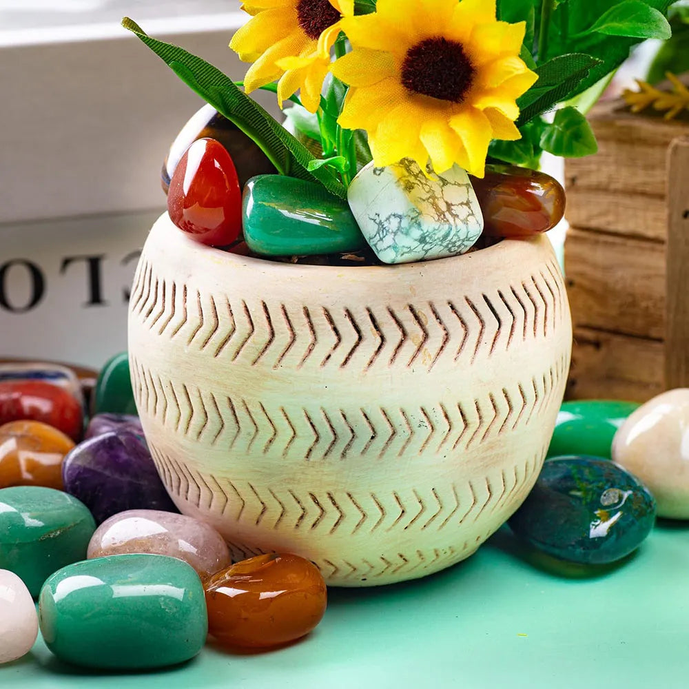 Decorative pot with sunflowers and colorful stones on a light green surface