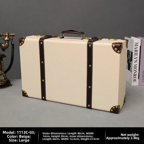 Beige suitcase with brown accents on a gray surface, with books and a vintage phone in the background.