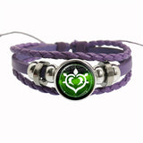Purple braided bracelet with a green heart-shaped charm on a white background