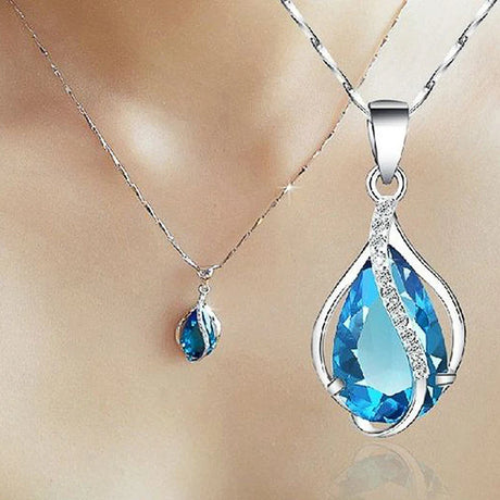 Blue teardrop pendant on a silver chain against a beige background