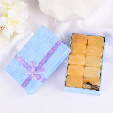 Box of square yellow candies with a purple ribbon on a white background