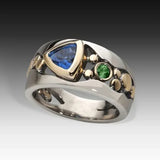 Silver ring with blue and green gemstones on a gradient background