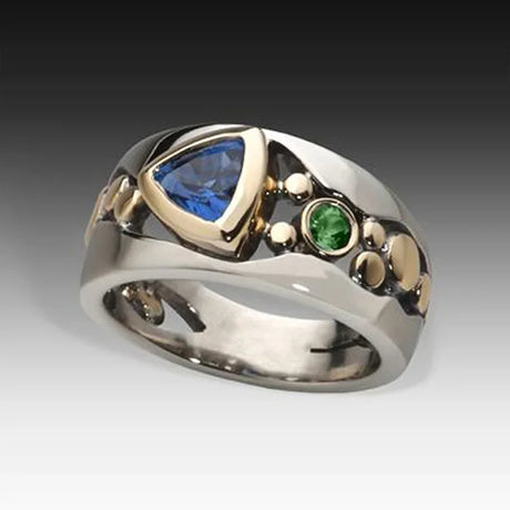 Silver ring with blue and green gemstones on a gradient background