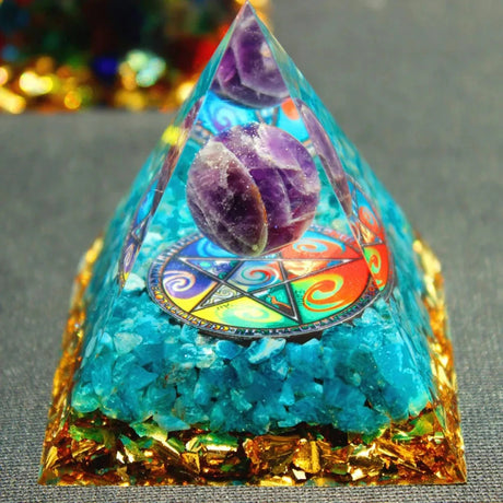 Crystal pyramid with colorful gemstones on a gray surface