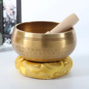 Gold singing bowl with a wooden striker on a white background