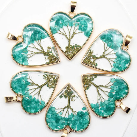 Five heart-shaped pendants with green floral designs on a white background