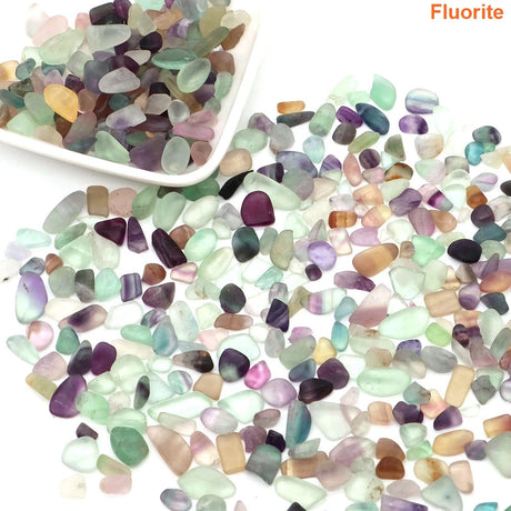 Multicolored fluorite stones with a white dish on a white background