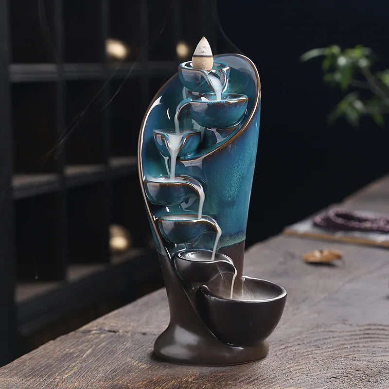Decorative water fountain with blue liquid and a candle on a wooden surface.