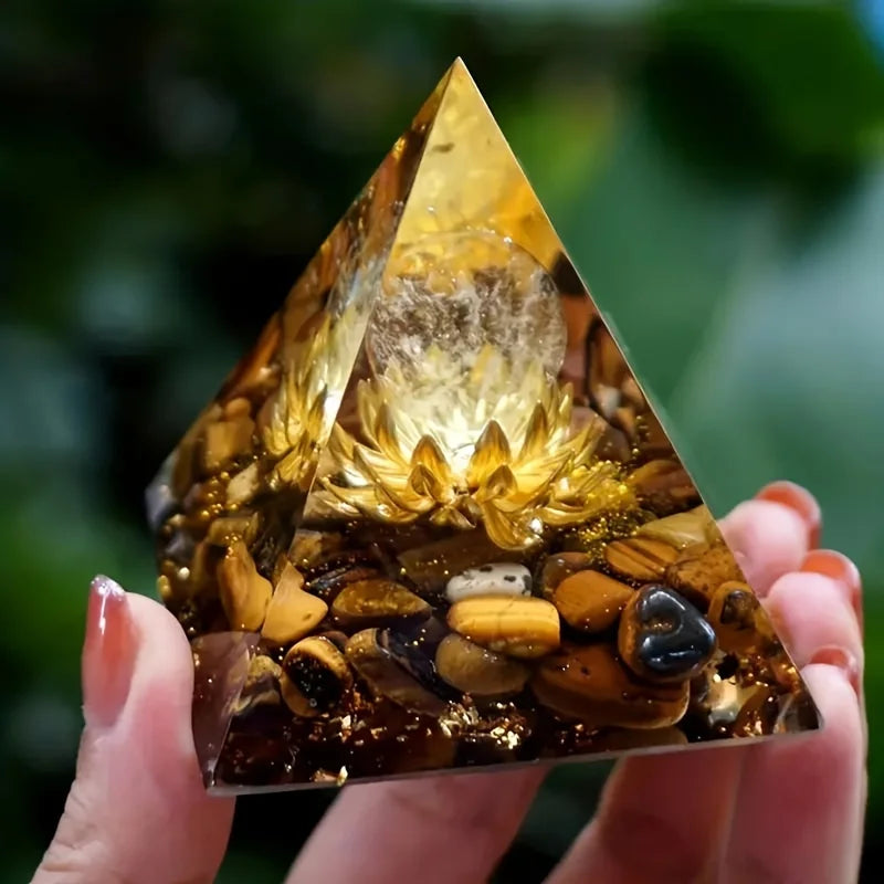 Triangular crystal pyramid held by a hand with a blurred green background