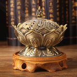 Decorative incense burner with intricate design on a wooden stand against a blurred background.