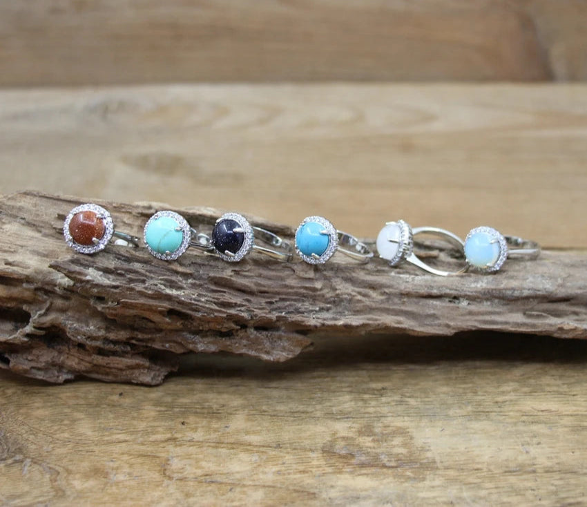 Set of silver rings with colorful gemstones on a wooden surface