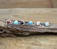 Set of silver rings with colorful gemstones on a wooden surface