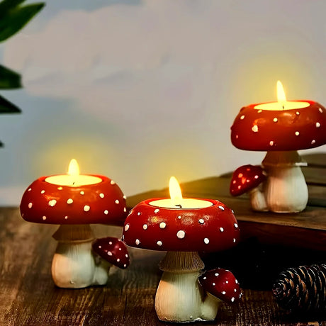 Three mushroom-shaped candles with red caps and white spots on a wooden surface.