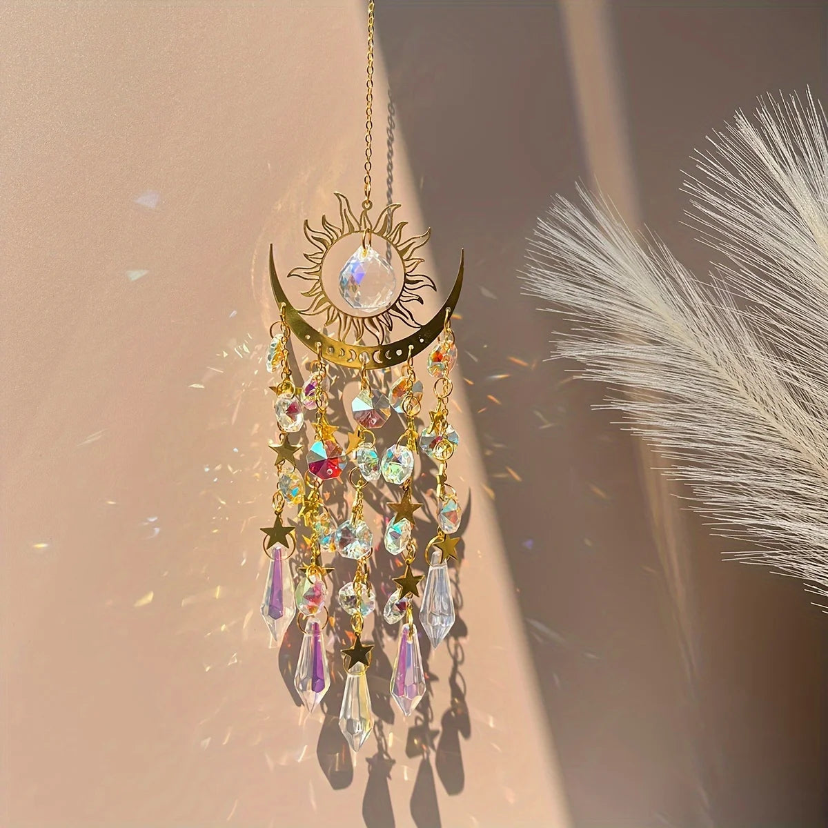 Decorative hanging ornament with crystals and sun design on a neutral background