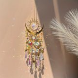 Decorative hanging ornament with crystals and sun design on a neutral background