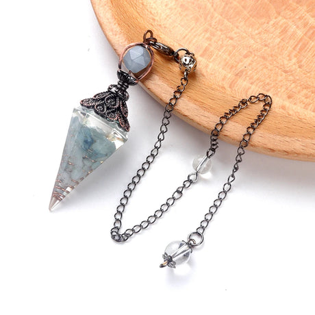 Crystal pendulum with chain on a wooden surface