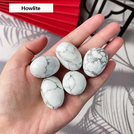 Hand holding five howlite stones with a decorative background