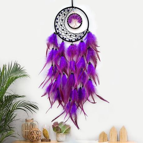 Purple feather dreamcatcher hanging on a white wall with decorative items below.