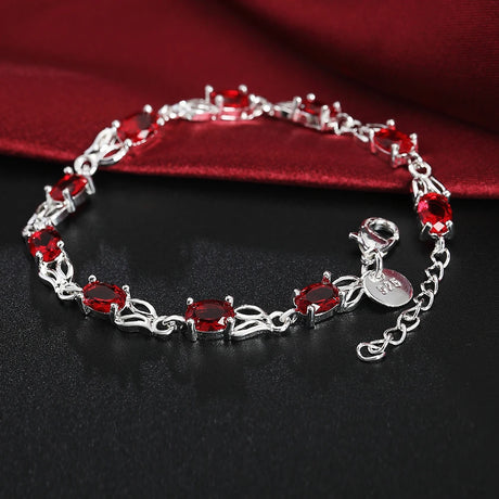Silver bracelet with red gemstones on a dark surface