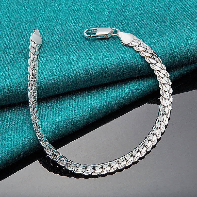 Silver chain bracelet on a teal fabric background