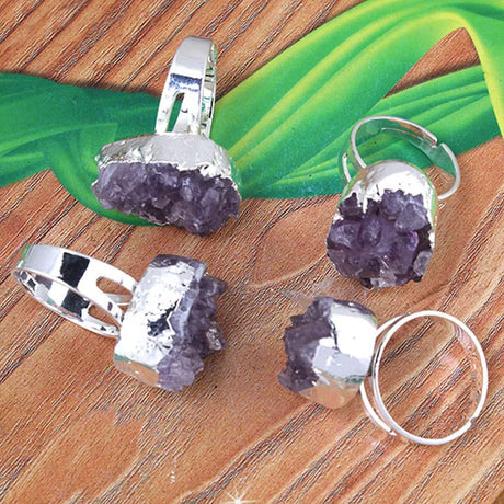 Silver rings with purple gemstones on a wooden surface
