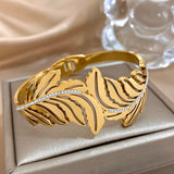 Gold bracelet with leaf design on a beige surface