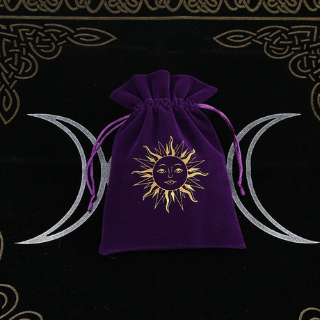 Purple drawstring bag with sun and moon design on a black background with wiccan symbols.