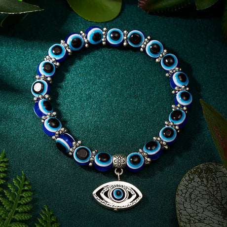 Blue and black beaded bracelet with an eye charm on a green fabric background