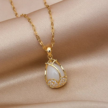 Gold necklace with a teardrop-shaped pendant on a beige fabric background