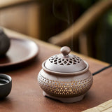 Ceramic incense burner with a perforated design on a wooden surface