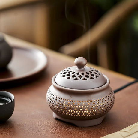Ceramic incense burner with a perforated design on a wooden surface