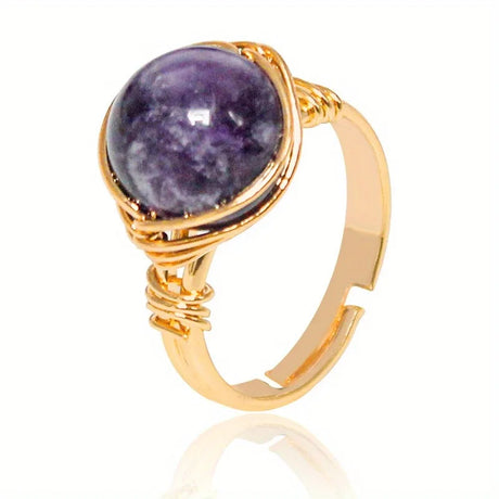 Gold ring with a purple stone on a white background