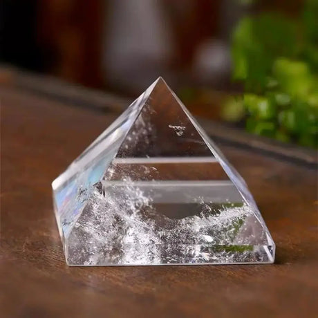 Clear crystal pyramid on a wooden surface with a blurred background