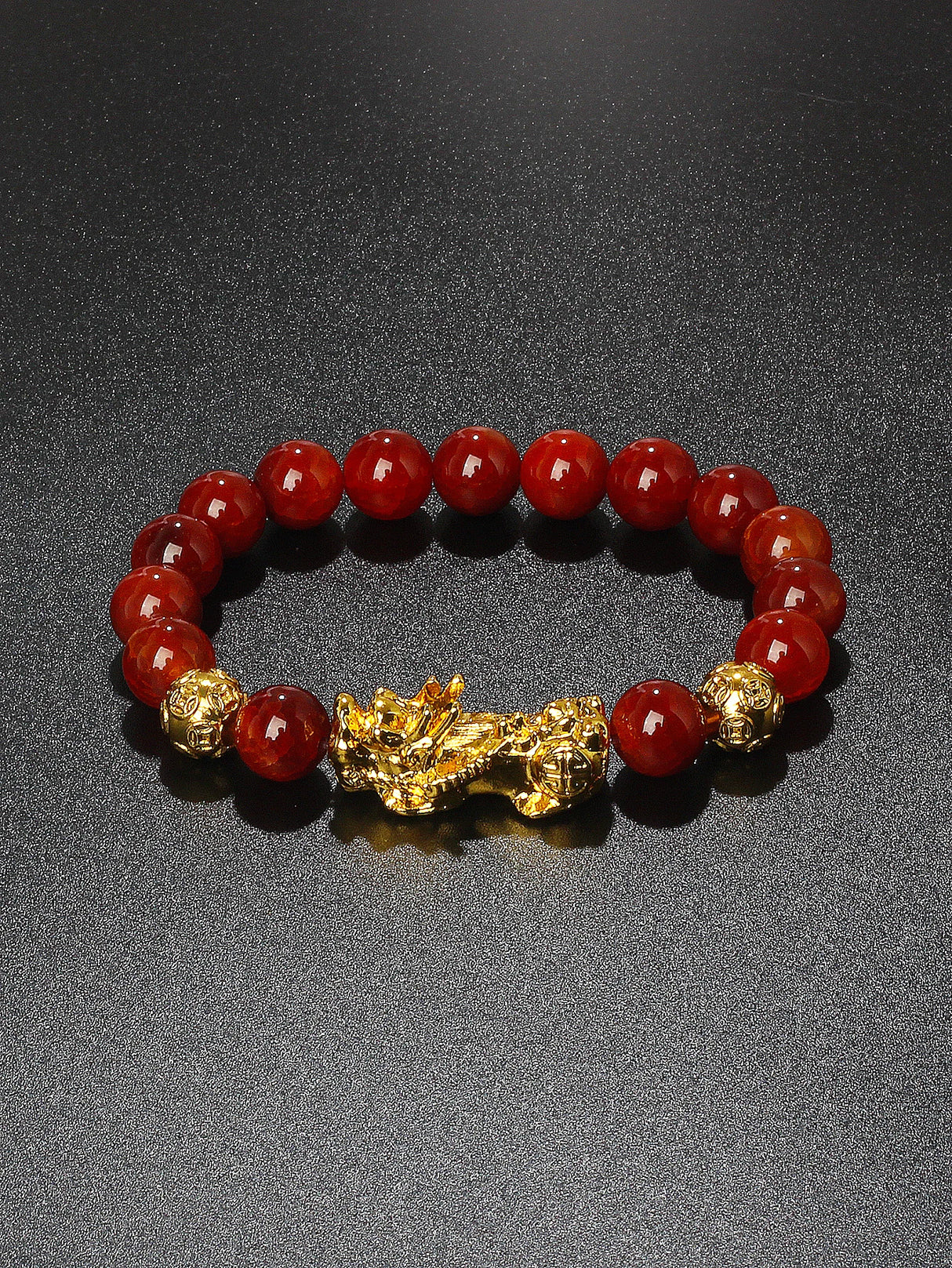 Red beaded bracelet with a gold dragon charm on a dark background