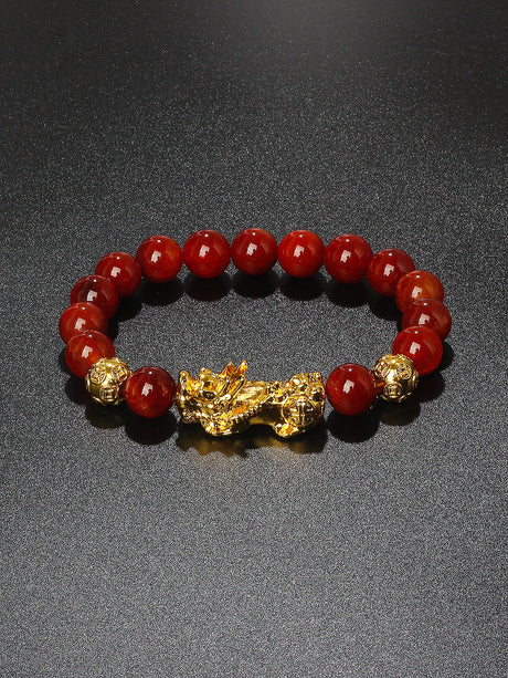 Red beaded bracelet with a gold dragon charm on a dark background