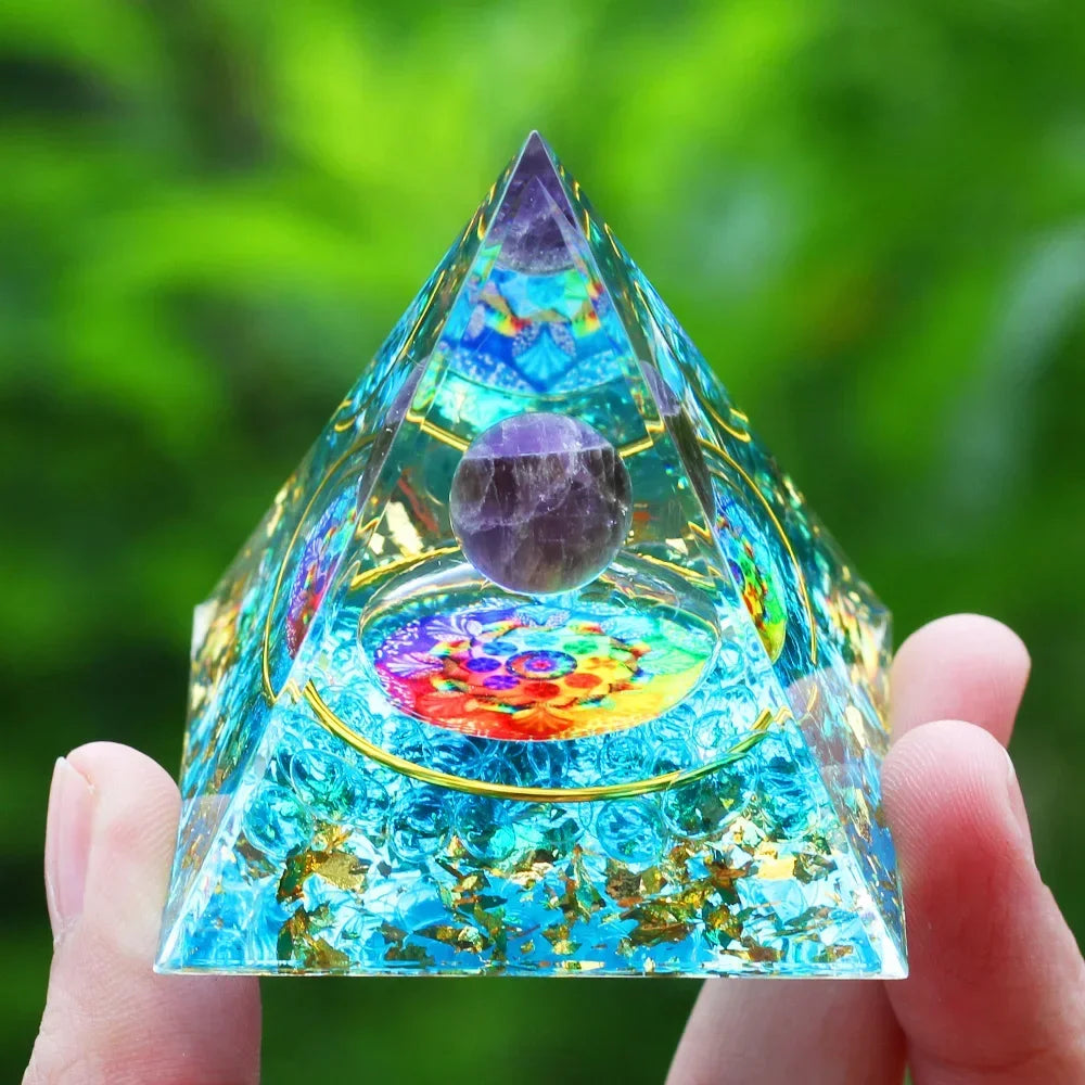Crystal pyramid with colorful interior held by a hand against a green blurred background