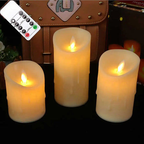 Three flameless candles with remote control in front of a suitcase.