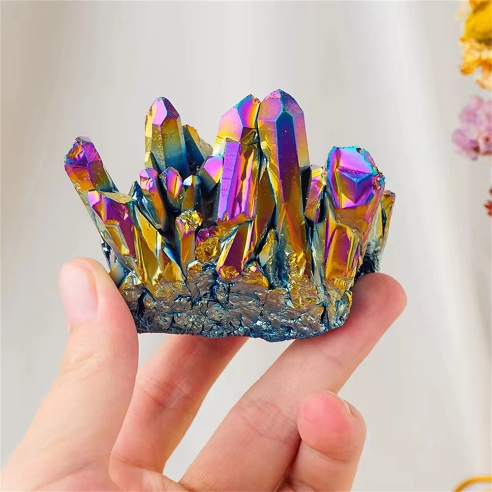 Multicolored crystal cluster held in a hand against a neutral background